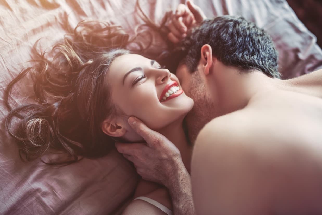 ベッドのなかで首筋にキスされた微笑む外国人女性の画像