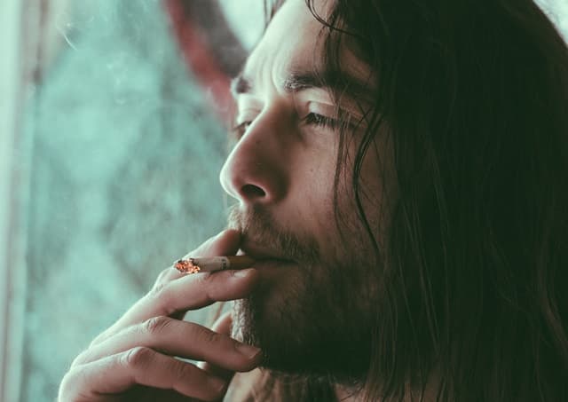 長髪の男性がタバコを吸っている画像