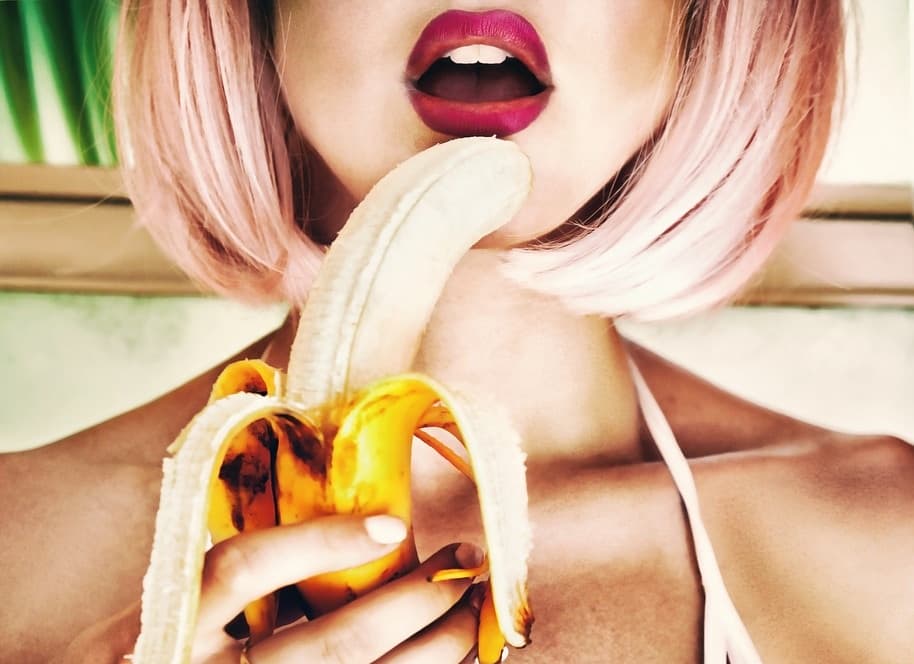 水着姿の女性がバナナを手に持って口にあてがっている画像