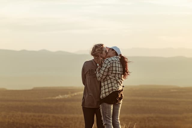 レズビアン女性2里が草原で2人振り向きざまにキスしている画像