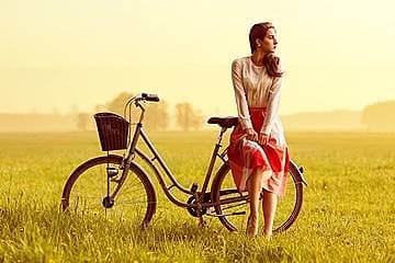自転車に腰掛けながら黄昏る女性の画像