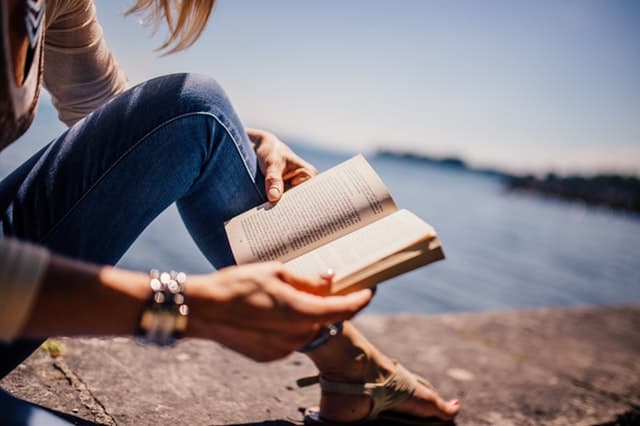海辺で本を読む女の子の手元の画像