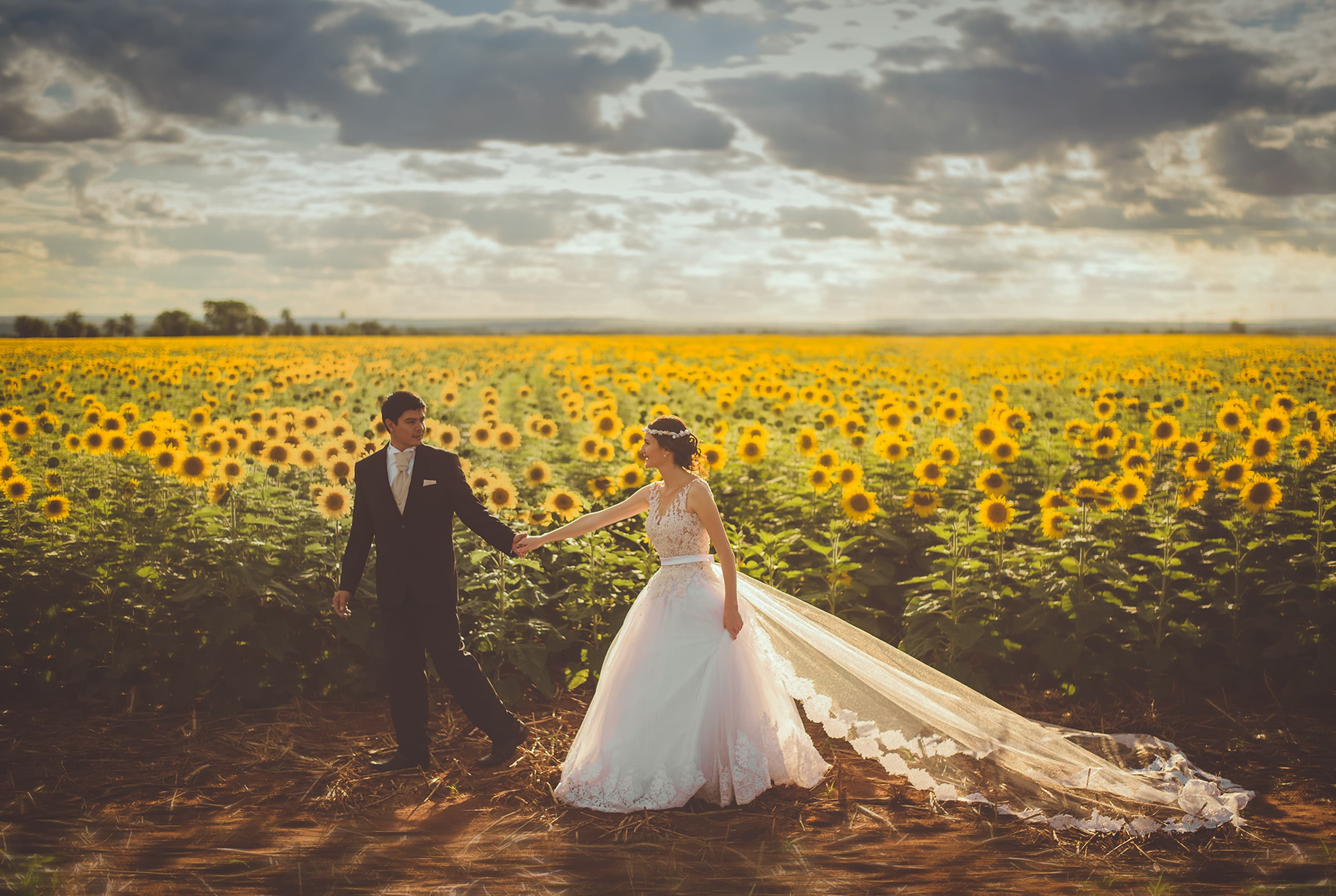 結婚したカップルが花畑を歩く画像
