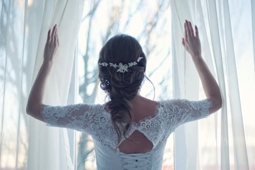 窓を開けるウェディングドレスの女性の画像