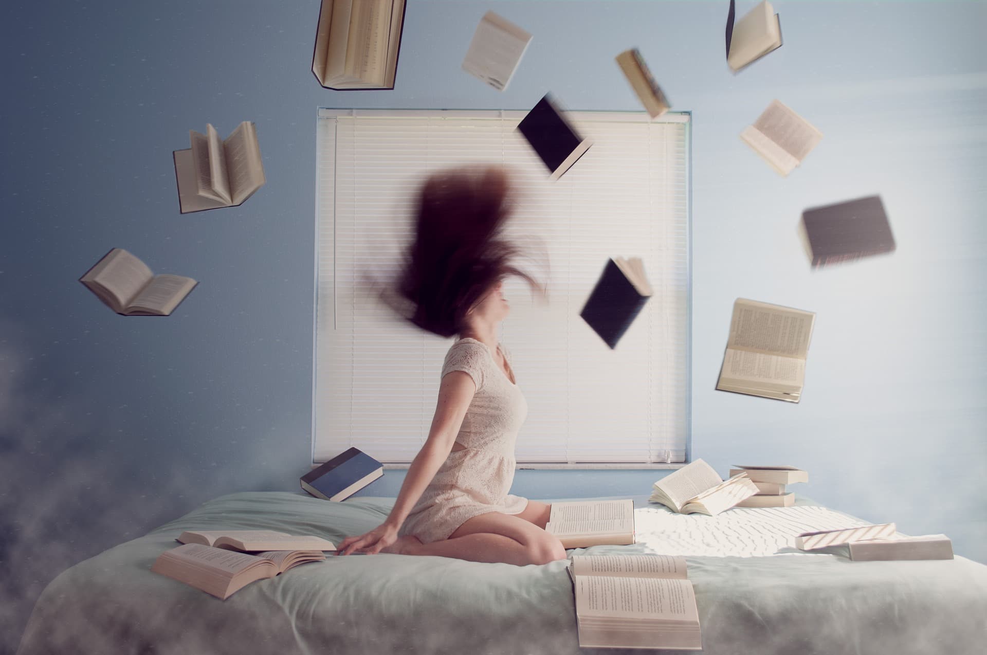 ベッドに座り本を散らばして荒ぶる女性の画像