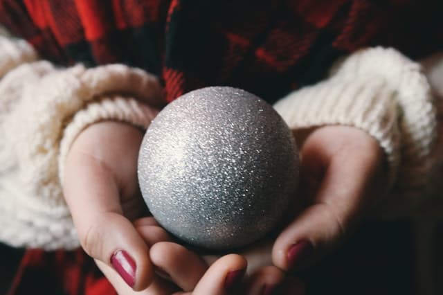 クリスマスのオーナメントのボールを手に持つ女性の画像