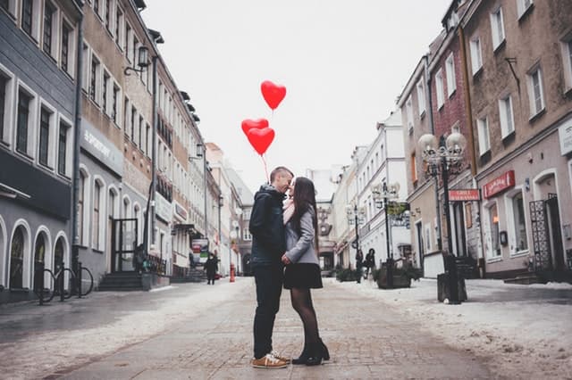 ハートの風船をもって街中で寄り添うカップルの画像
